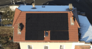 Seize panneaux solaires photovoltaïques installés sur une toiture en tuiles rouges d'une maison individuelle.