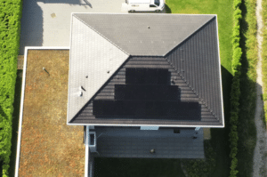 Maison moderne vue de dessus avec panneaux photovoltaïques sur le toit et une toiture végétalisée adjacente.